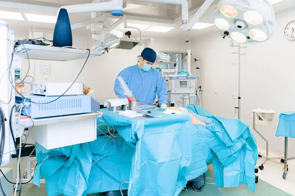 Doctor in surgical attire performing operation in a well-equipped operating room.